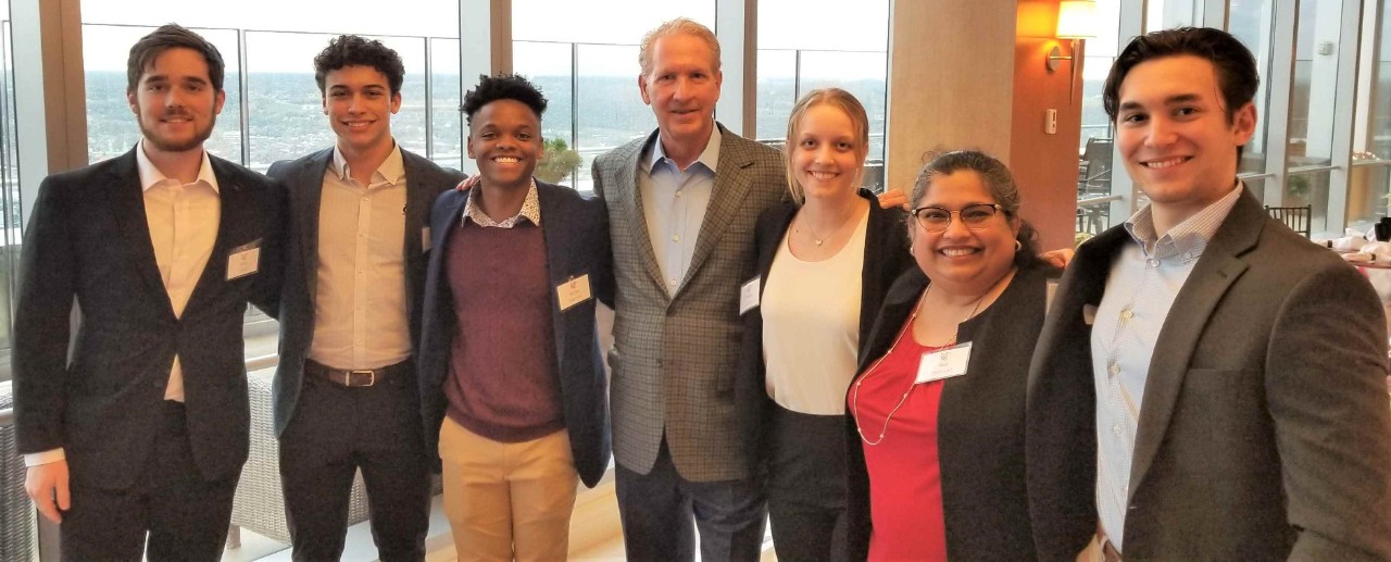 Students and working professionals in a group photo, a skyline in the background.